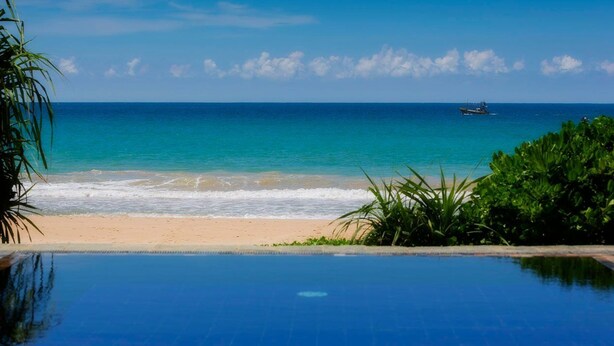 A beach with a clear blue sky, ocean, and a swimming pool. - Villananda by Interhome (Ambalangoda)