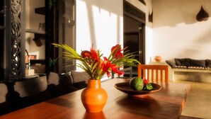 A wooden table with a vase of red flowers and a bowl of fruit. - Villananda by Interhome (Ambalangoda)