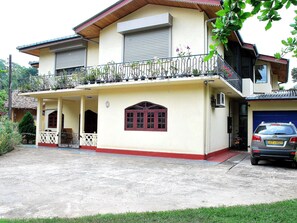 A two-story house with a balcony, a garage, and a front porch. - Dominic's Home by Interhome (Weligama)