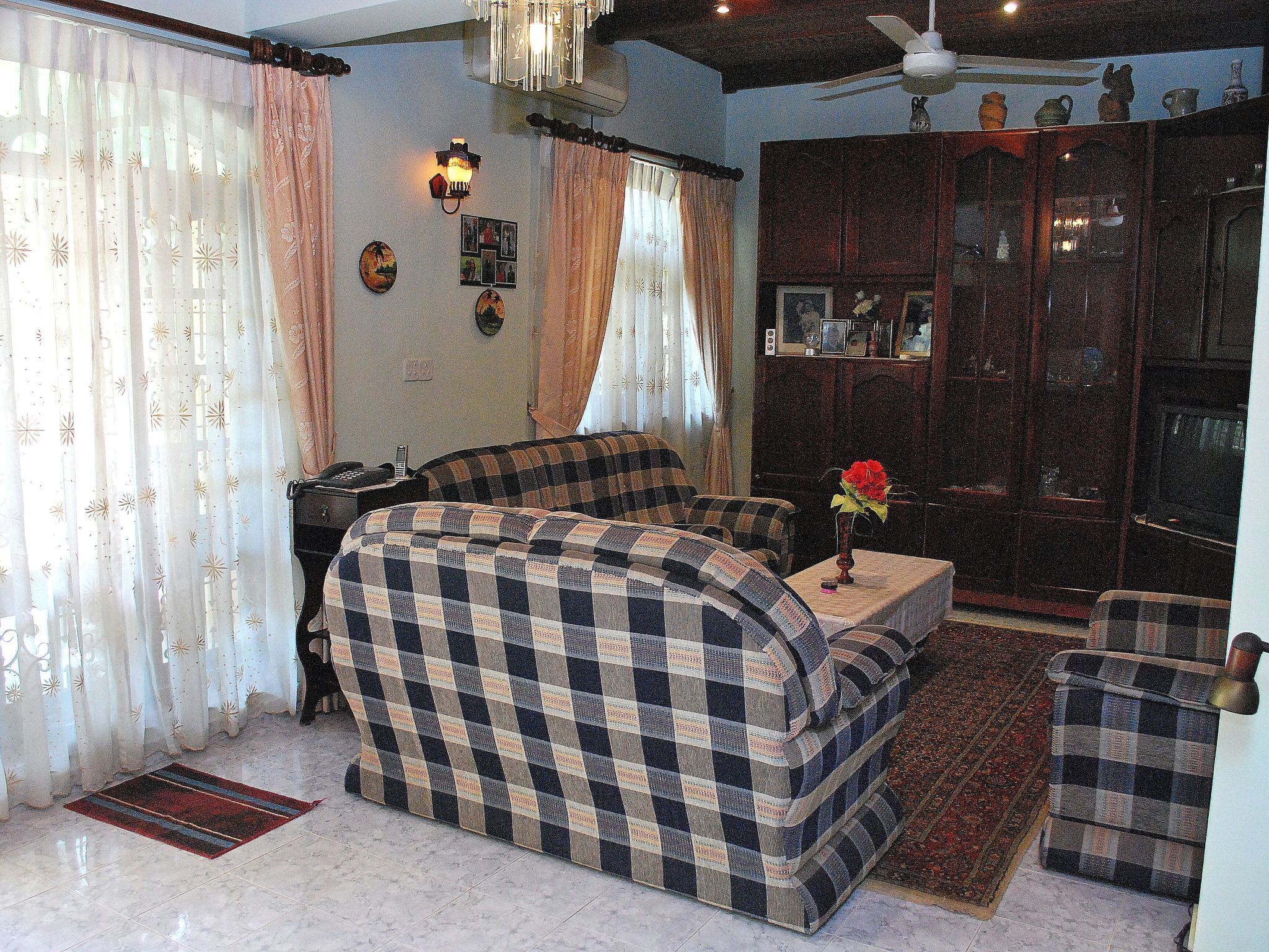 A living room with a sofa set, a small table with a vase, and a cabinet with decorative items.