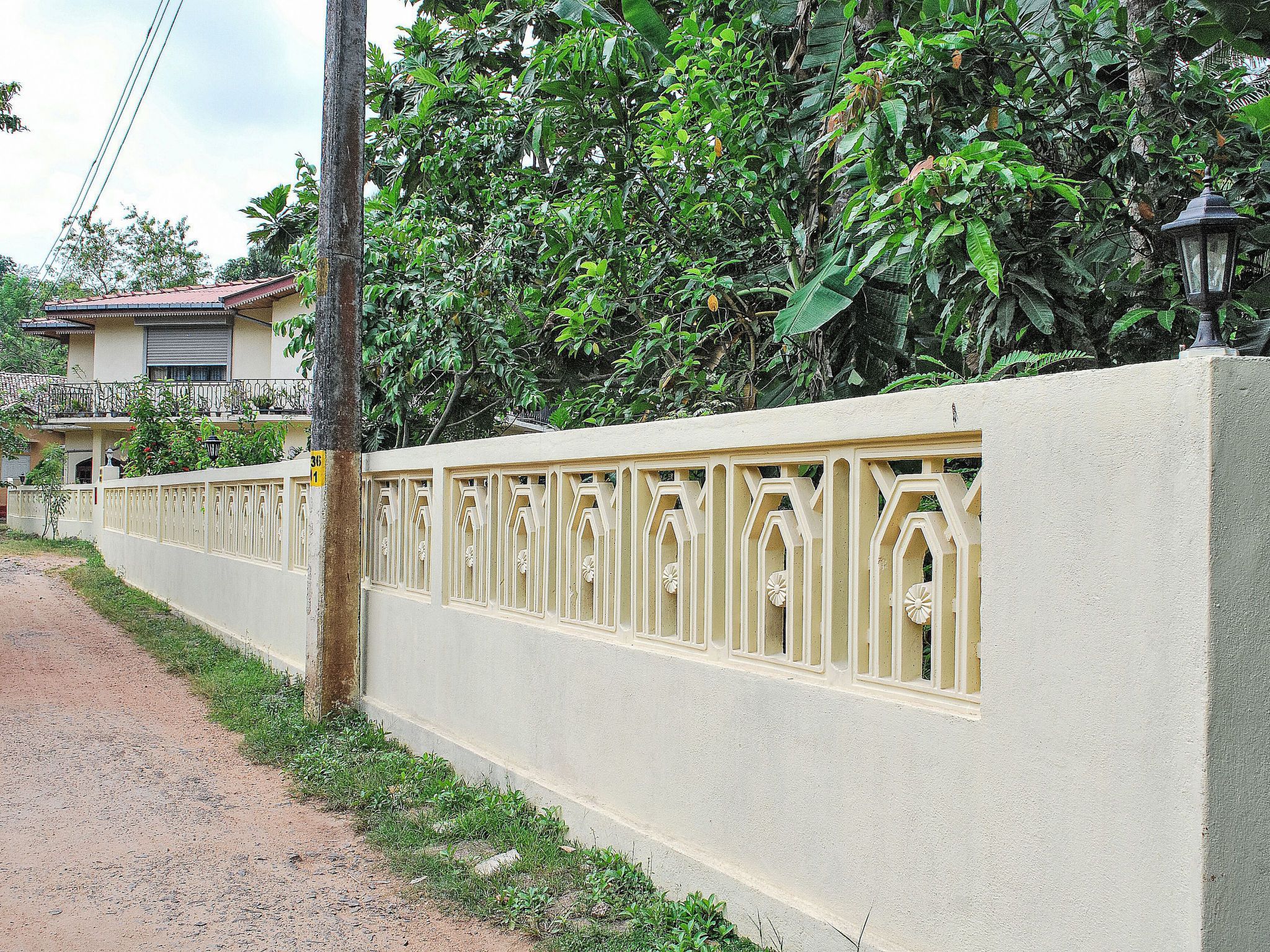 A residential area with a concrete wall, a metal fence, and a tree.