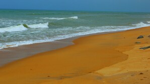 Ein sandiger Strand mit an die Küste rollenden Wellen unter blauem Himmel.