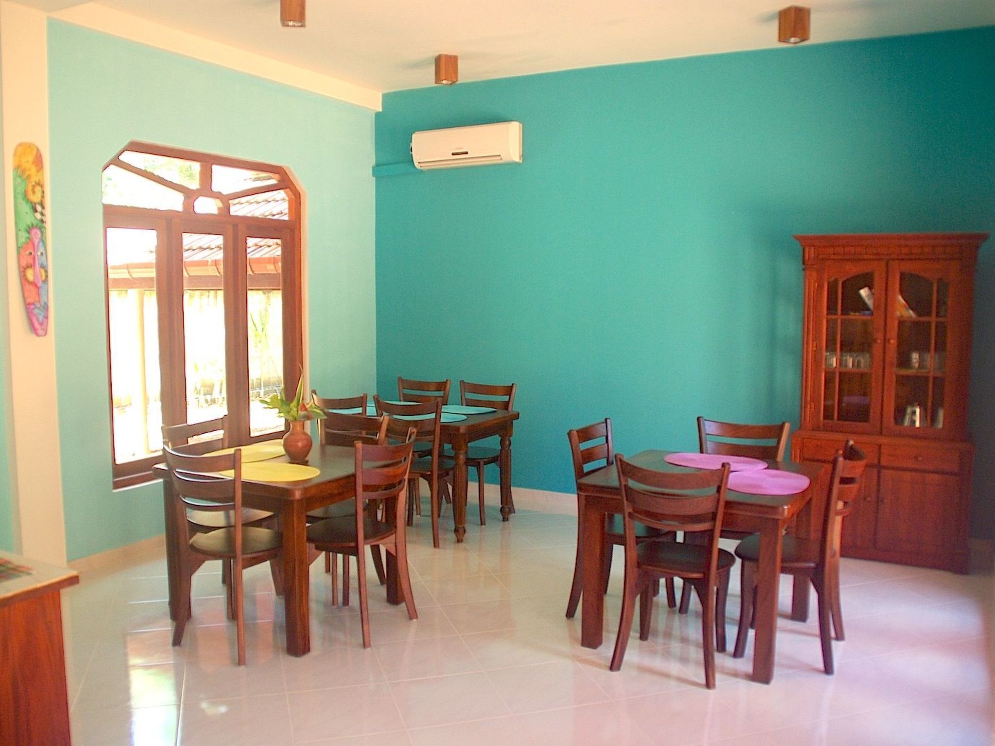 A dining area with a round table and chairs, a cabinet, and a window with curtains.