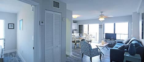 A spacious living area with a dining table, chairs, a sofa, and a television.