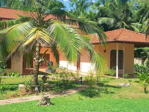 A bungalow with a tiled roof, surrounded by lush greenery and palm trees. - Peacock by Interhome (Habaraduwa /Galle)