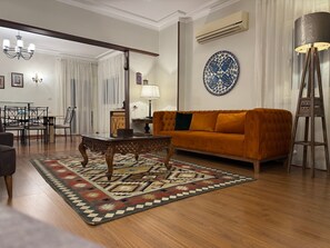 A living room with a sofa, coffee table, and patterned rug. There is a dining area with chairs and a table in the background. - mit Flussblick in Zamalek Kairo by Interhome (Cairo)