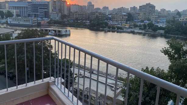 Eine Stadtansicht mit einem Fluss, Gebäuden und einem Sonnenuntergang.