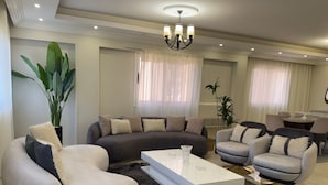 A modern living room with a sectional sofa, a round coffee table, and a dining area with a table and chairs. - Wohnung "Zayed Continental G" by Interhome (Cairo)