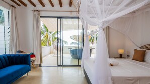 Ein Schlafzimmer mit einem Bett, einem blauen Sofa, einer Glastür, die auf einen Balkon führt, und einem Deckenventilator.