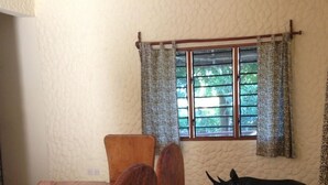 Ein Essbereich mit einem Holztisch, Stühlen, einer dekorativen Tiervorrichtung, einem Fenster mit Vorhängen und einer Pendelleuchte.