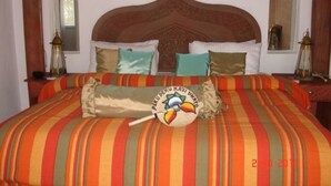 Un letto con copriletto a righe e cuscini, un cuscino decorativo con un motivo a uccello e due comodini con lampade.