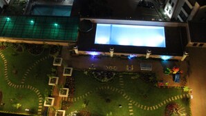 Vue aérienne d’un hôtel avec une grande enseigne lumineuse, une piscine et un jardin aménagé.