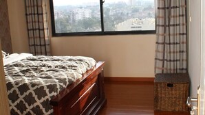 Une chambre avec une grande fenêtre, un lit et un plancher en bois.