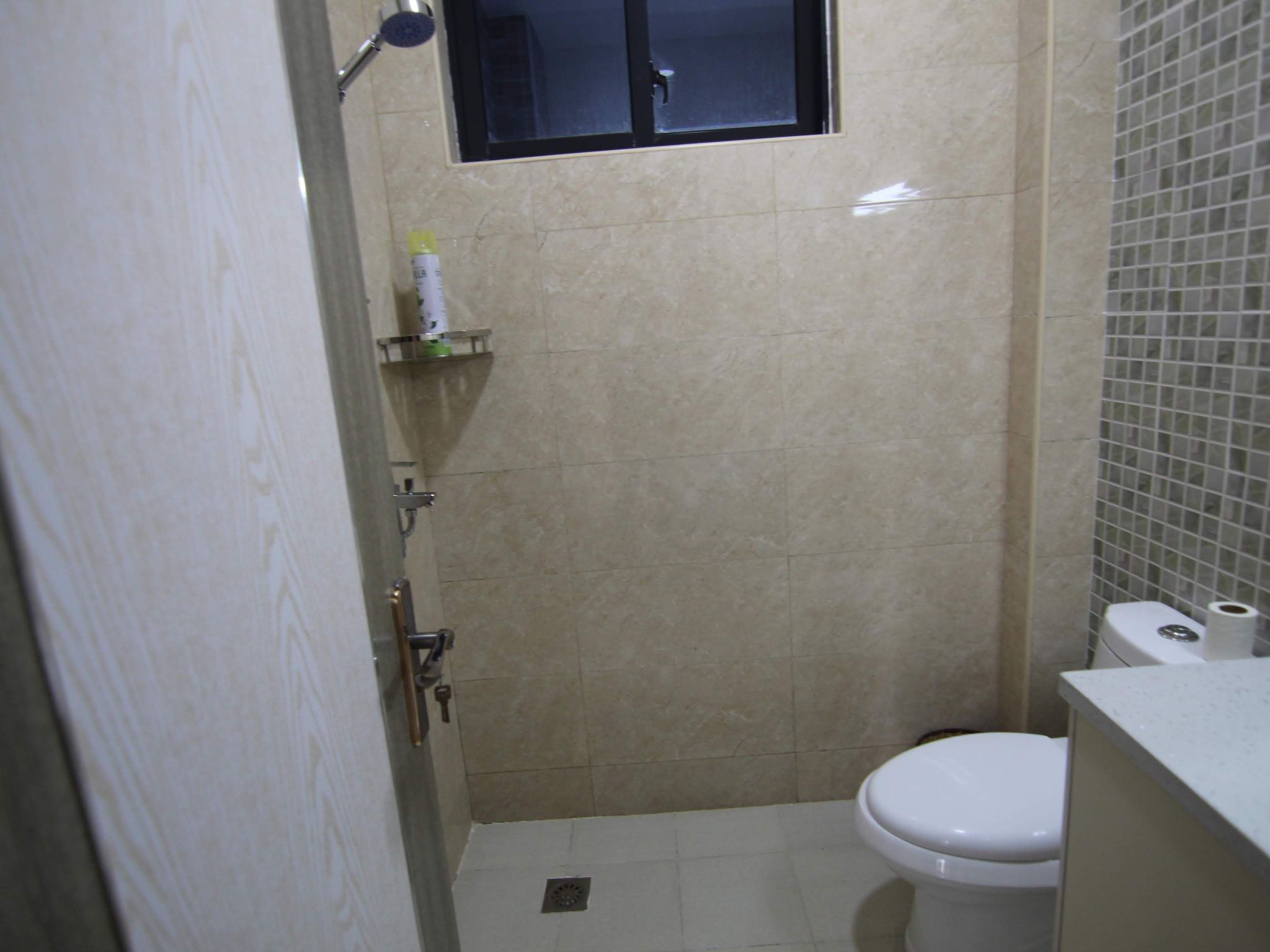 Une petite salle de bain avec des toilettes, une douche et une fenêtre.