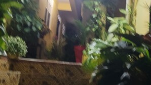 Eine Treppe führt zu einem überdachten Bereich, der von beiden Seiten mit Blumentöpfen geschmückt ist.