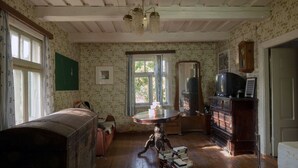 Une pièce avec un plancher en bois, une table ronde, un miroir, un téléviseur et une bibliothèque.