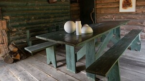 L’intérieur d’un chalet rustique en bois, avec une grande table, des bancs et un tableau encadré accroché au mur.