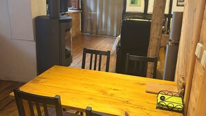 Una mesa de comedor de madera con cuatro sillas, una estufa negra y un suelo de madera.