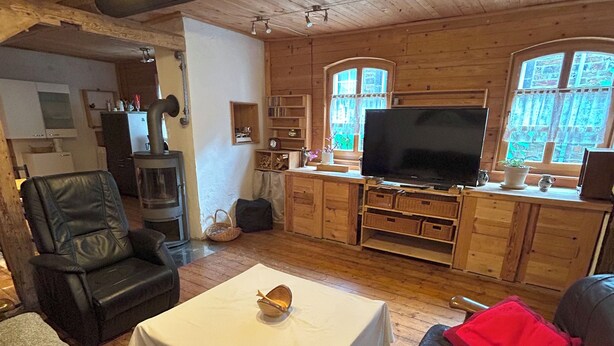 Una sala de estar acogedora con chimenea, muebles de cuero, televisor y armarios de madera.