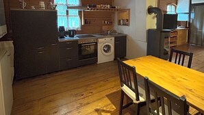 Cocina funcional con armarios de madera, lavadora y comedor con mesa y sillas.