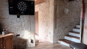 A rustic room with exposed wooden beams, a dartboard, a wooden cabinet, and a staircase leading to an upper level. - Country house with jacuzzi and pets allowed (Saint-Joire)