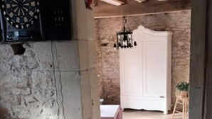 A rustic room with exposed wooden beams, a dartboard, and a white door leading to another room. - Country house with jacuzzi and pets allowed (Saint-Joire)