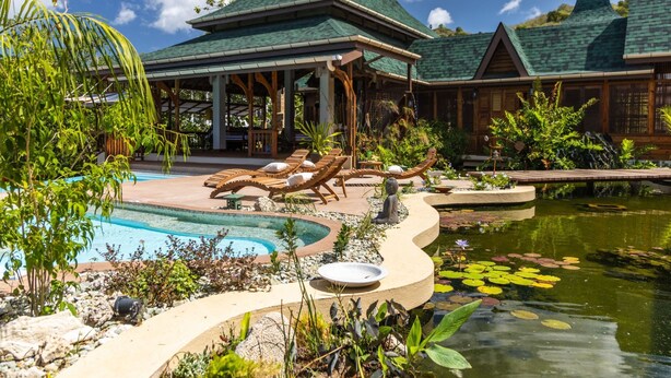 Un resort con piscina, sillas de descanso y un estanque con nenúfares.