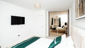 A modern hotel room with a large bed, a flat-screen TV mounted on the wall, and a sliding glass door leading to a bathroom. - The Prime Stay Free Parking EV Charger (Sittingbourne)