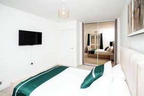A modern hotel room with a large bed, a flat-screen TV mounted on the wall, and a sliding glass door leading to a bathroom. - The Prime Stay Free Parking EV Charger (Sittingbourne)