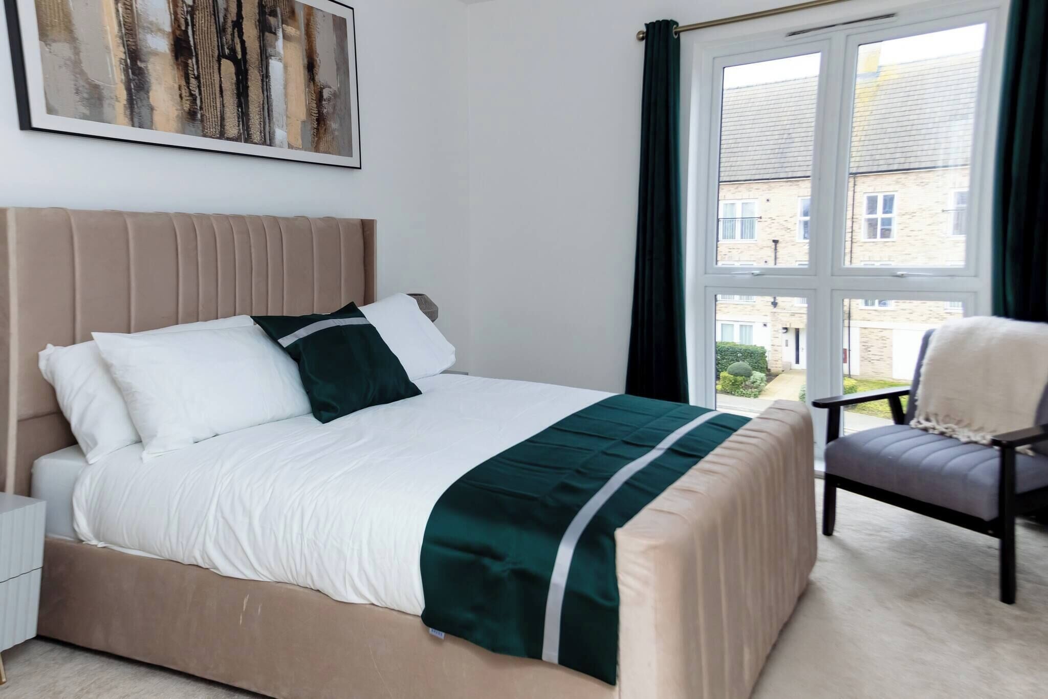 Ein ordentlich eingerichtetes Schlafzimmer mit Bett, Stuhl und einem fenster mit Vorhängen.