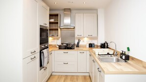 A compact kitchen with white cabinets, a stainless steel sink, and a wooden countertop. - The Prime Stay Free Parking EV Charger (Sittingbourne)