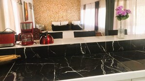 Une cuisine moderne dotée d’un plan de travail en marbre noir, d’un mur en pierre et d’un coin repas avec un canapé et des coussins.