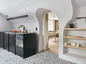 Une cuisine moderne avec un plan de travail noir, des appareils en acier inoxydable et un revêtement de sol imitant la pierre.