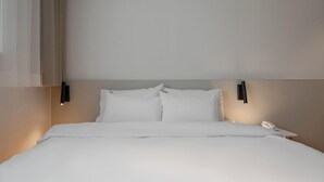 A neatly made bed with white linens, a bedside phone, and wall-mounted light fixtures. - H Avenue Hotel Andong Culture Street (Andong)
