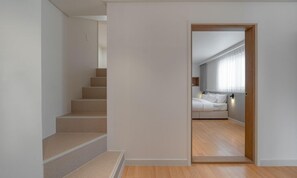 A staircase leading to a bedroom with a bed, a nightstand, and a window with curtains. - H Avenue Hotel Andong Culture Street (Andong)