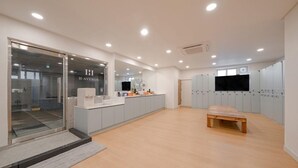A modern kitchen with a glass door entrance, a wooden bench, and a TV mounted on the wall. - H Avenue Hotel Andong Culture Street (Andong)