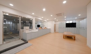 Una cocina moderna con entrada de puerta de cristal, un banco de madera y un televisor montado en la pared.