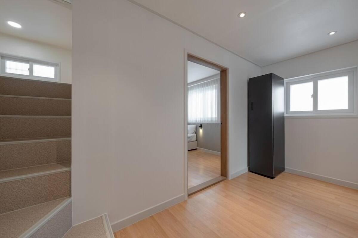A room with a staircase, a door leading to another room, and a window.