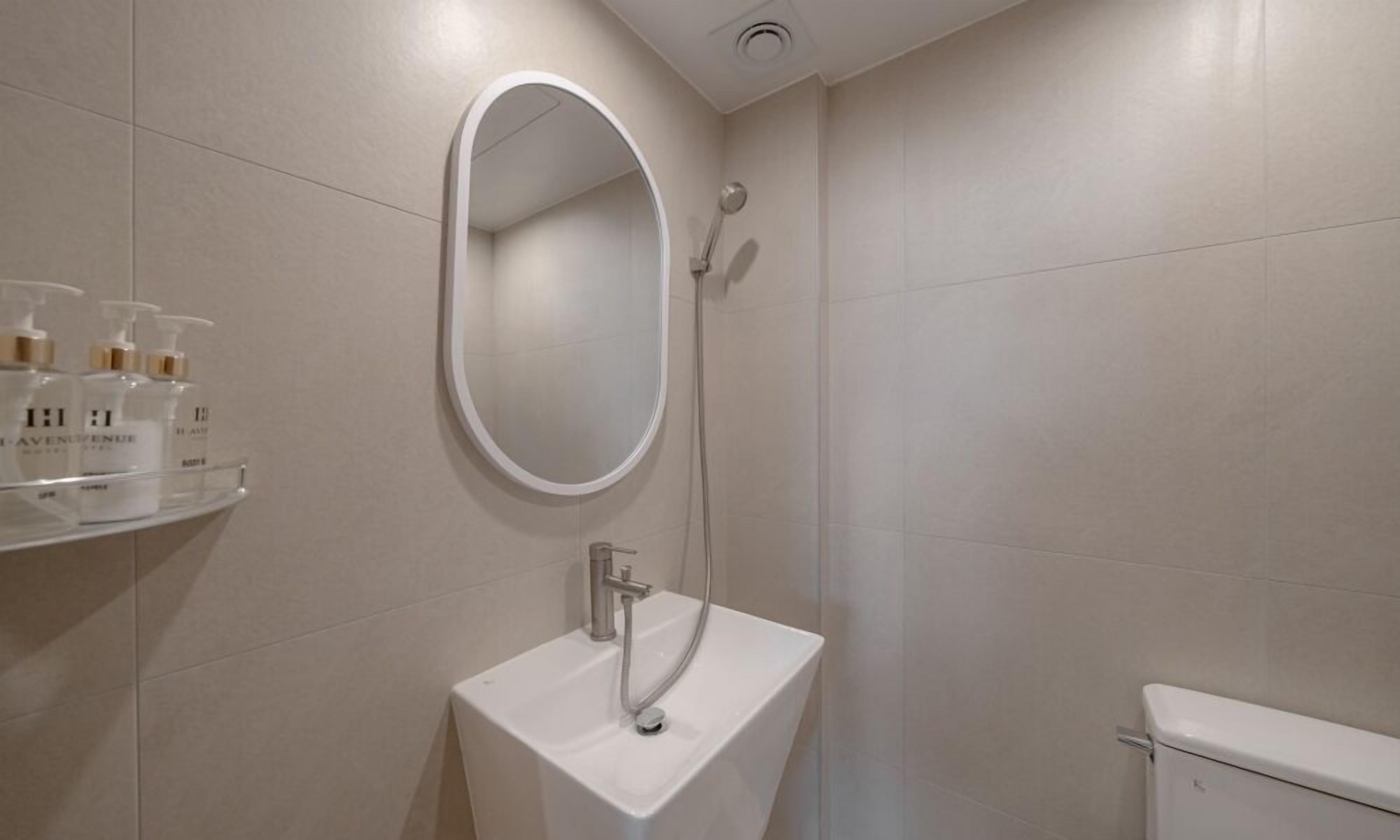 A modern bathroom with a white sink, a mirror, and a shower.