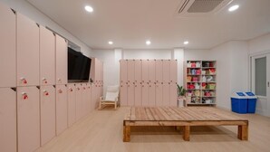 A room with lockers, a wooden table, a chair, and storage shelves. - H Avenue Hotel Andong Culture Street (Andong)