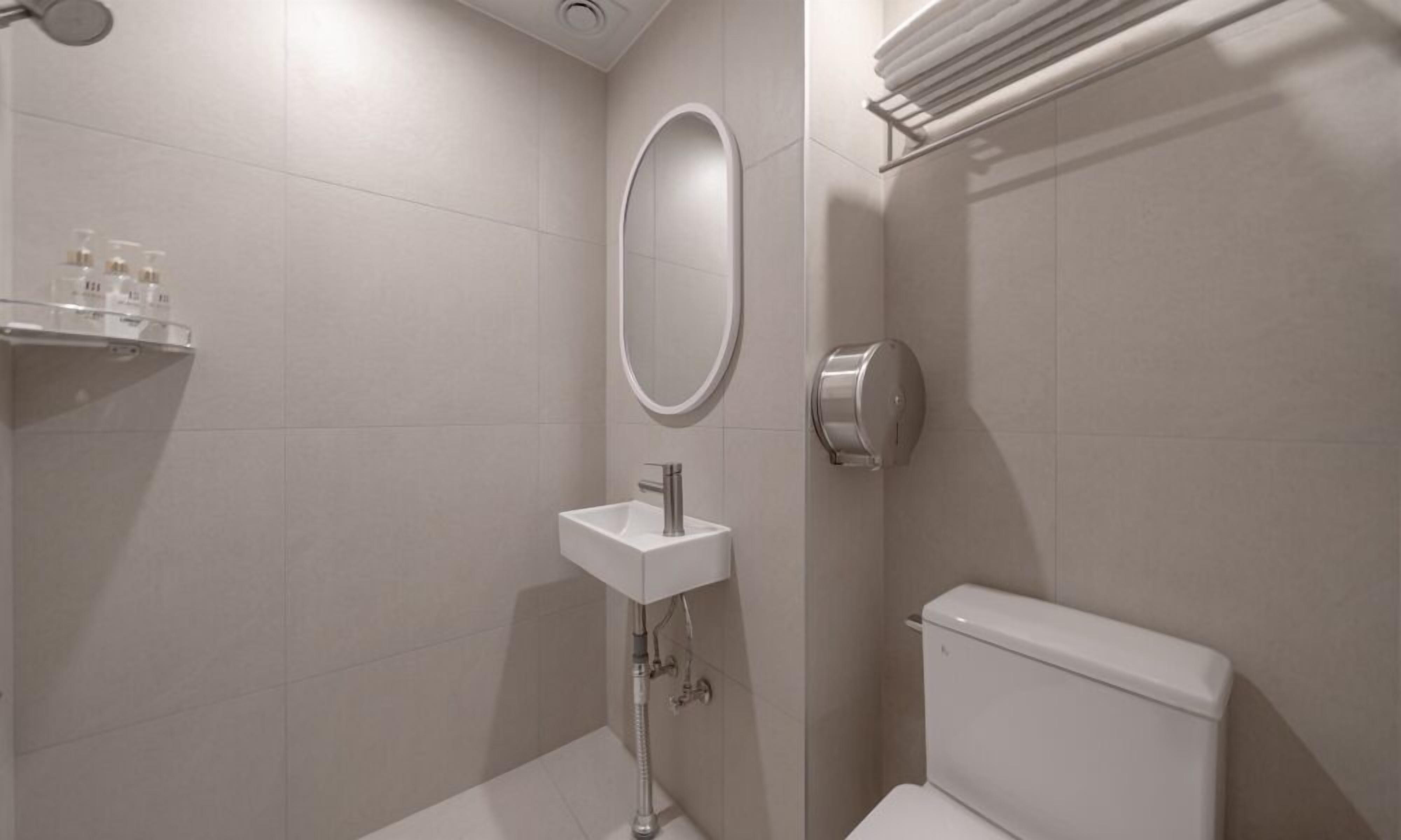 A modern bathroom with a white sink, toilet, and a mirror.