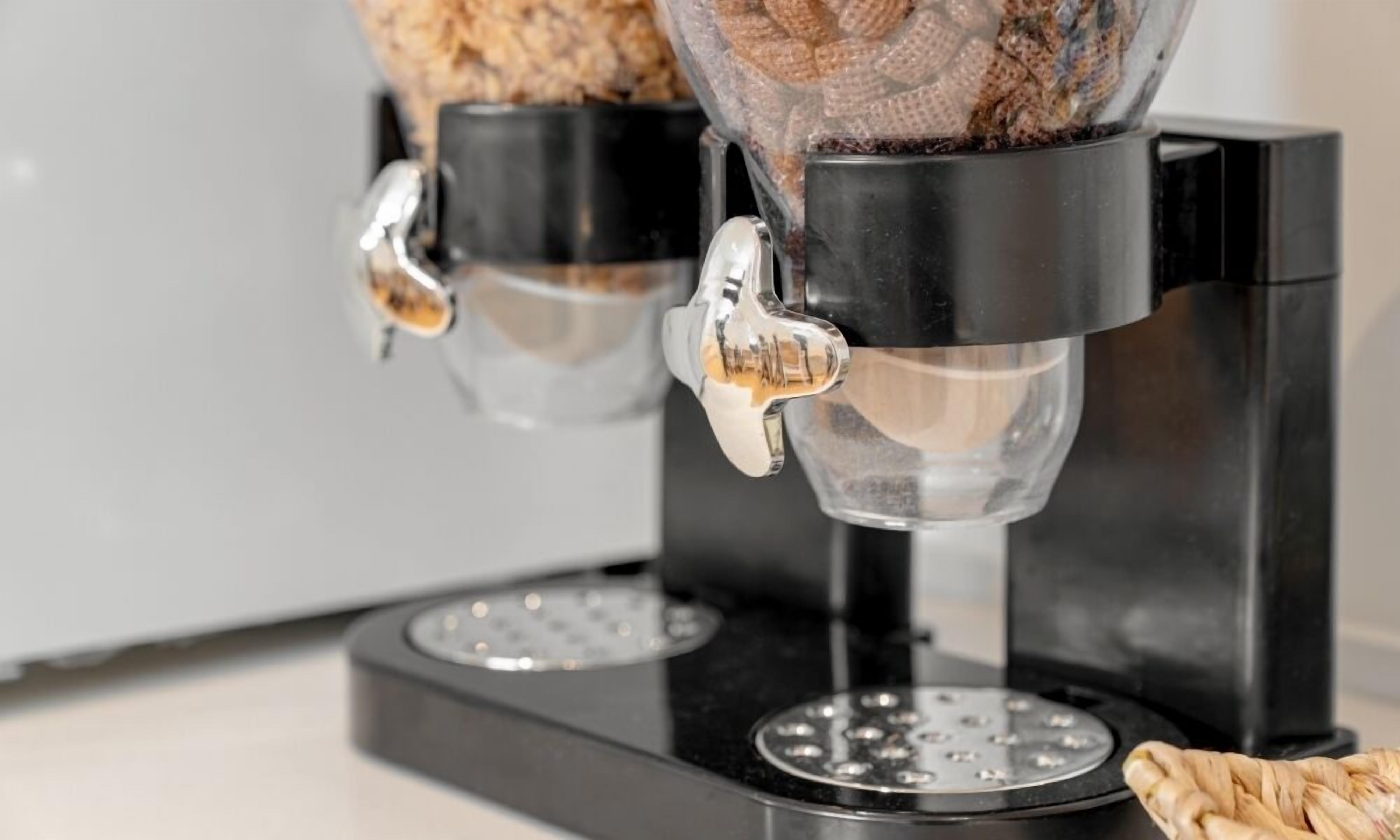 A coffee machine with two dispensers, a black base, and a stainless steel plate.