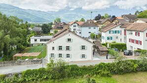 A vineyard with rows of grapevines and a white building with multiple windows and a balcony. - Hofstätte 37 by Interhome (Vaduz)