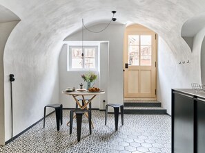 Une pièce dotée d’un sol carrelé en forme d’hexagone, d’une table ronde entourée de chaises, d’une fenêtre avec des rideaux et d’une porte donnant sur l’extérieur.