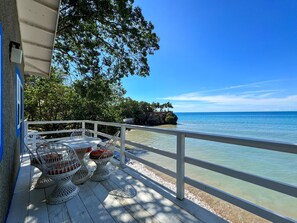 A wooden deck with outdoor seating, overlooking a clear blue sea and a rocky outcrop with trees. - Unvergessliches Cottage, eine Schönheit direkt a by Interhome (Treasure Beach)