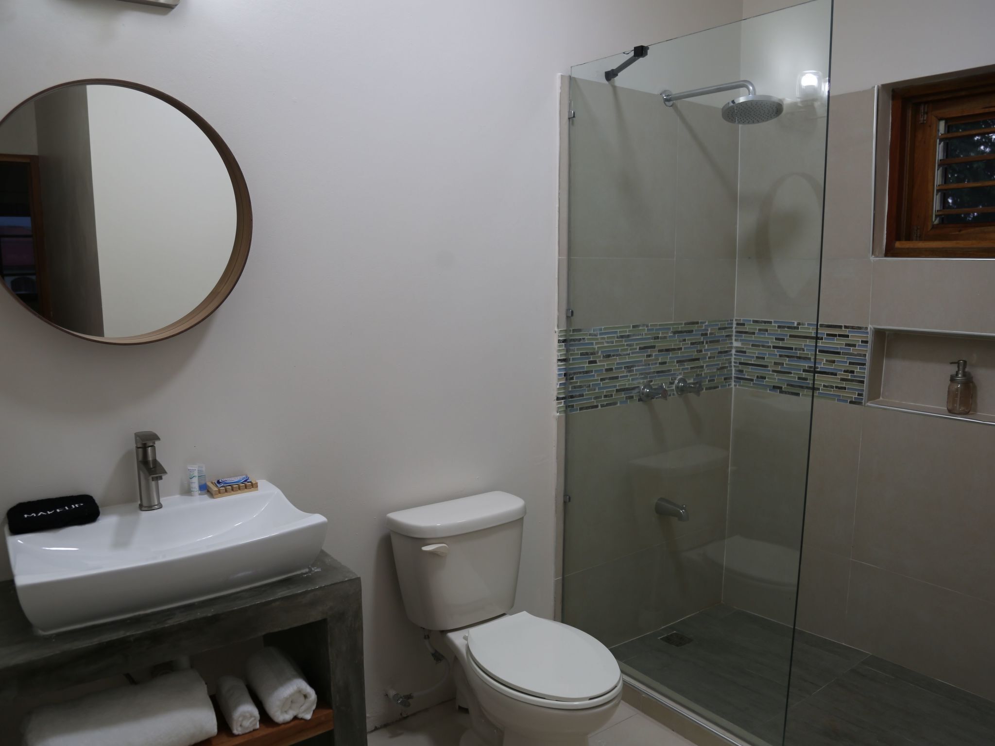 Une salle de bain avec une douche à parois de verre, un lavabo blanc et des toilettes.