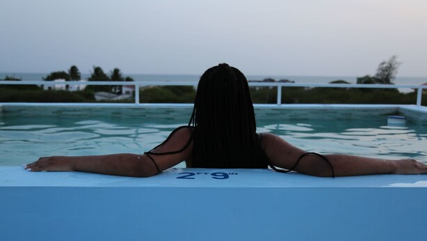 A person lying on a pool edge with a view of the ocean and a white railing. - VillaMerissa schmiegt sich zwischen zwei unber ührte Strände by Interhome (Belleair)