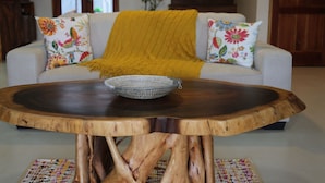 A living room with a round wooden coffee table, a sofa with floral cushions, and a yellow throw blanket. - VillaMerissa schmiegt sich zwischen zwei unberührte Strände by Interhome (Belleair)