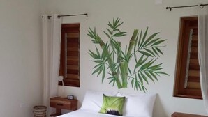 A bedroom with a bed, a nightstand, a bedside table, a wall-mounted plant, and a window with curtains. - VillaMerissa schmiegt sich zwischen zwei unberührte Strände by Interhome (Belleair)