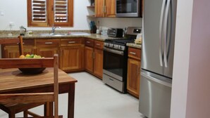 A kitchen with wooden cabinets, a stainless steel refrigerator, a microwave, a stove, and a sink. - VillaMerissa schmiegt sich zwischen zwei unberührte Strände by Interhome (Belleair)